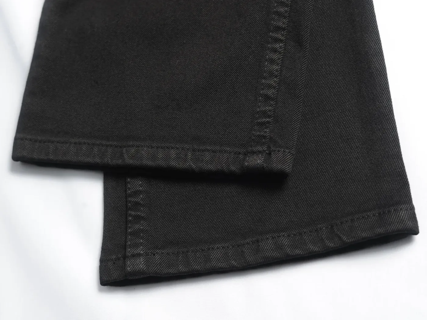 Detail jahitan hitam pada panel denim gelap