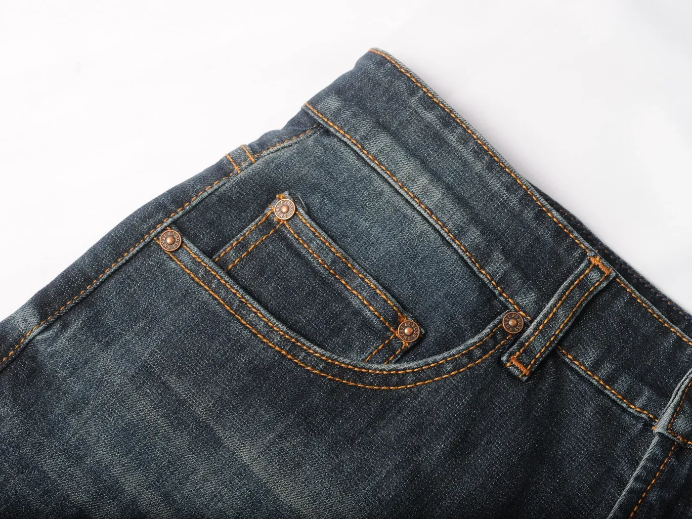 Detail rivet logam dan coin pocket pada bagian depan jeans