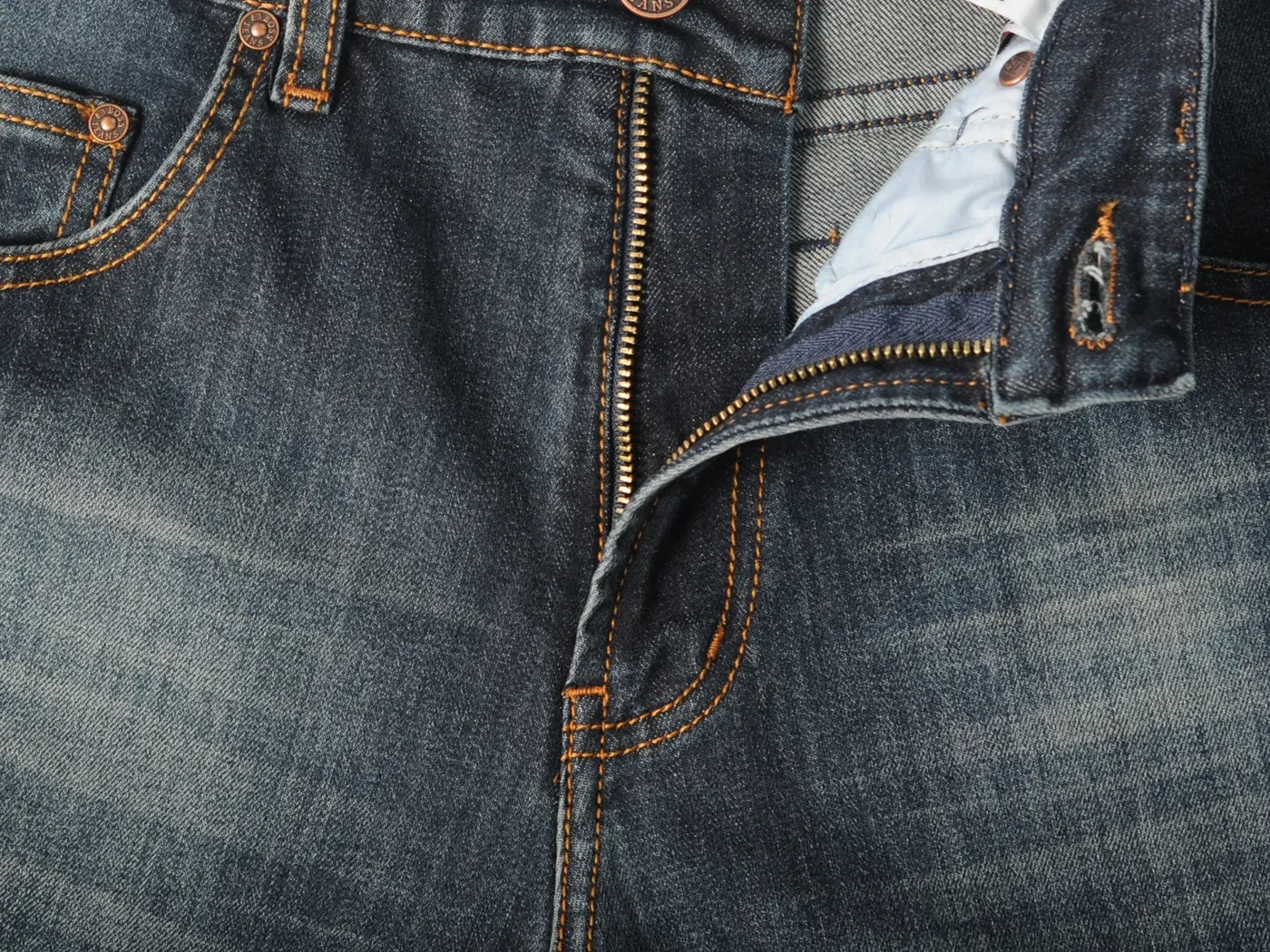 Detail zip fly dan hardware logam pada bukaan depan jeans